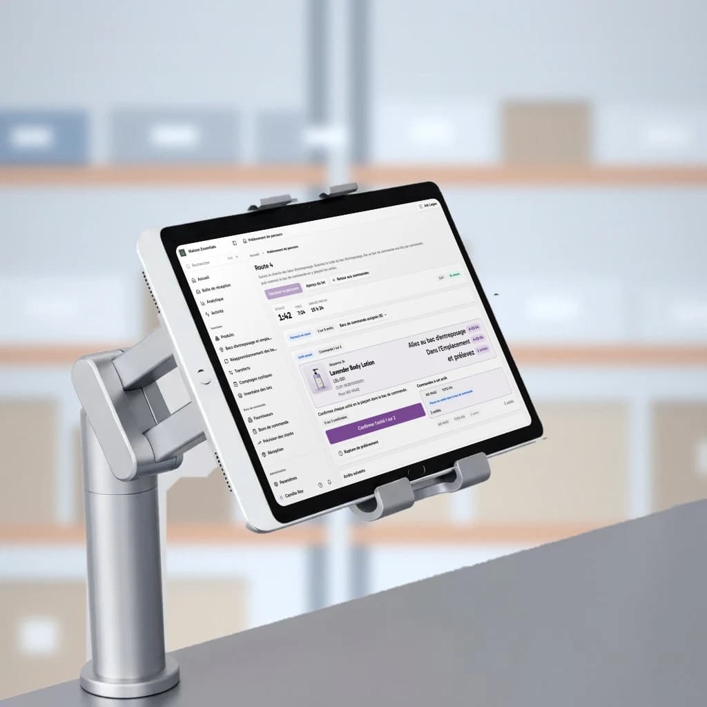 Un iPad affichant le trajet de prélèvement de Logentic sur le support en aluminium d'un poste d'emballage, dans un entrepôt